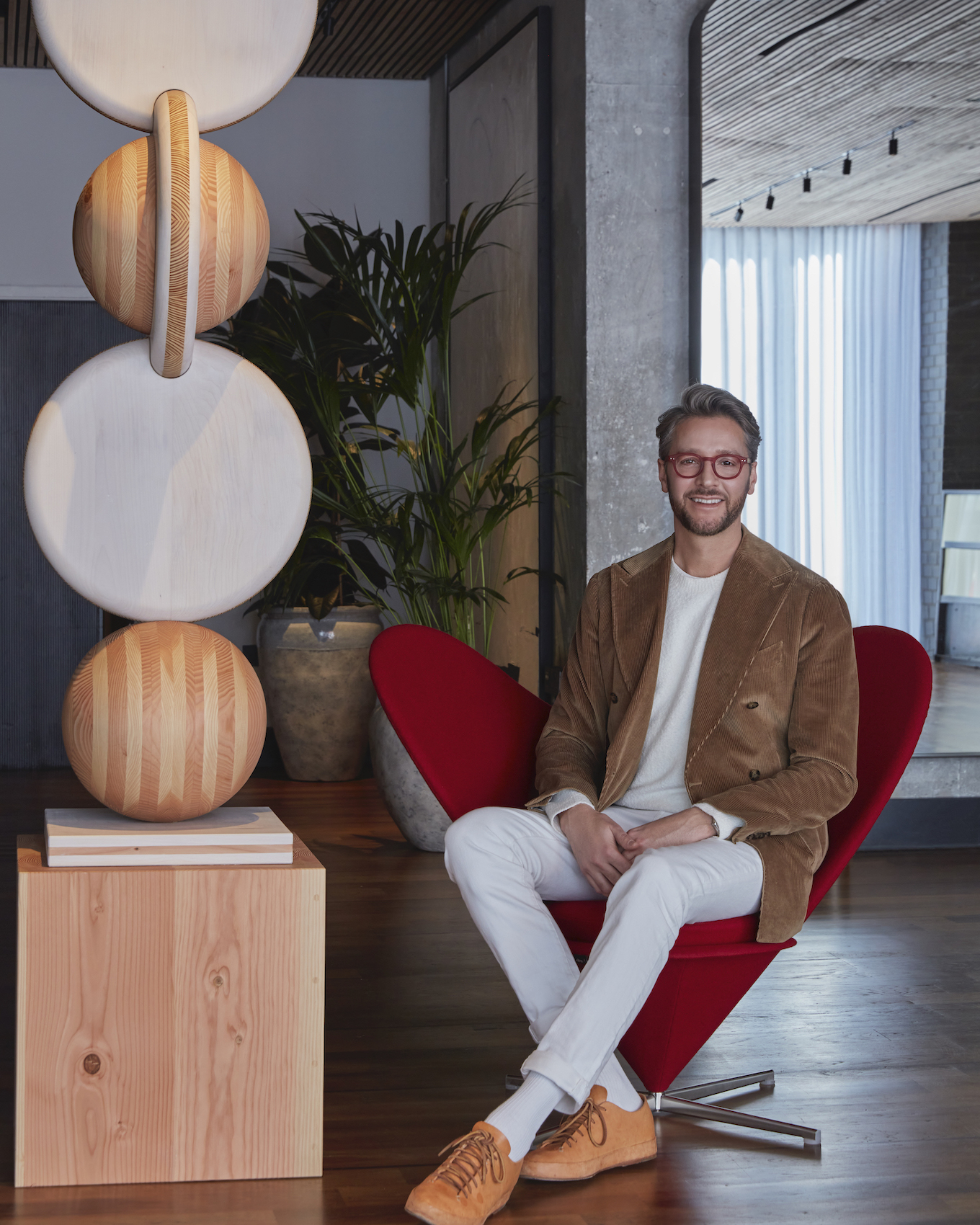 Jacu Strauss, creative director of the Lore Group of hotels, pictured on a Verner Panton heart chair in the lobby of One Hundred Shoreditch in London – Effect Magazine
