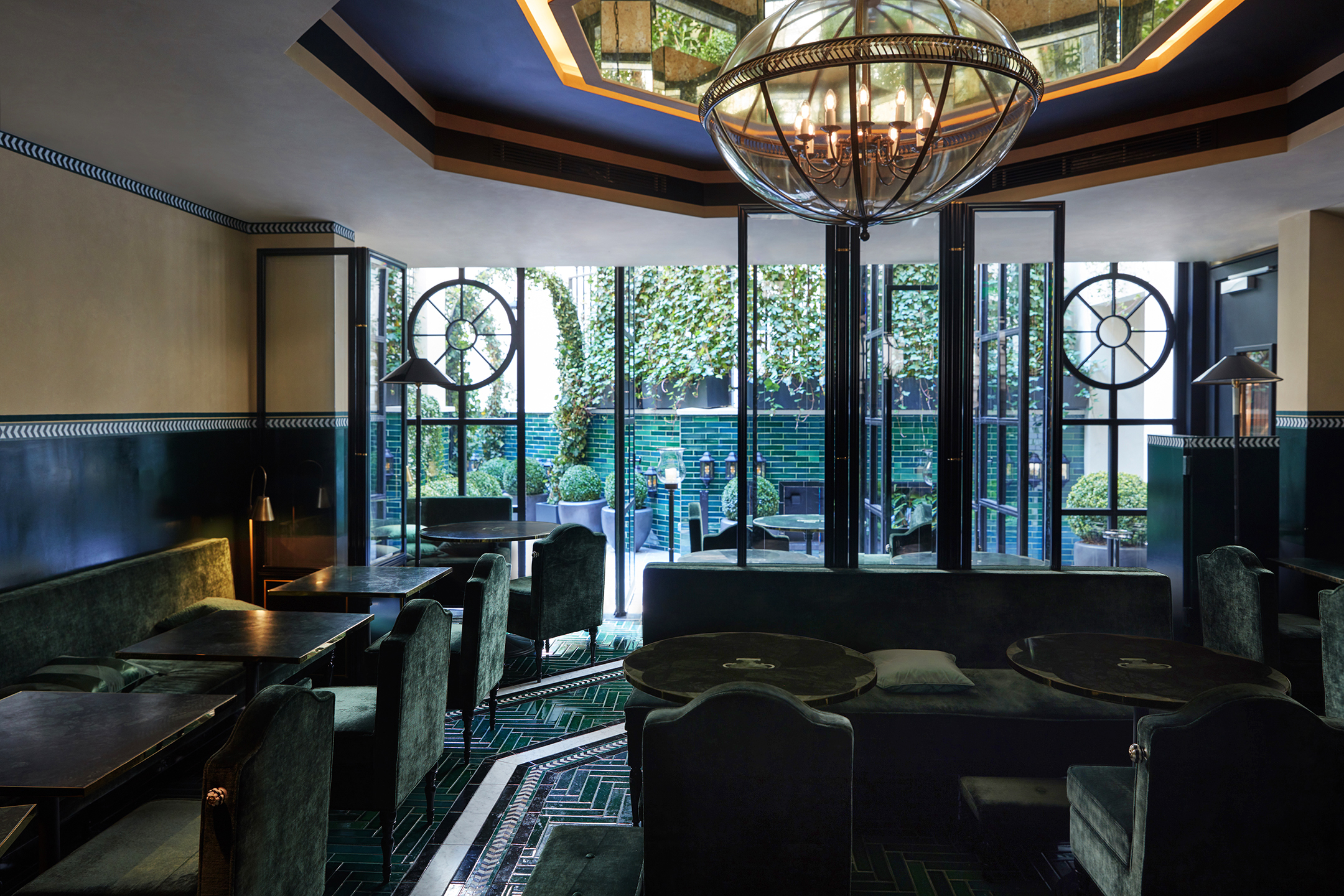 Emerald-green velvet seating with brass bag holders and Moroccan floor tiles at Galanga Restaurant, Monsieur George Hotel, Paris, interior designed by Anouska Hempel - Effect Magazine