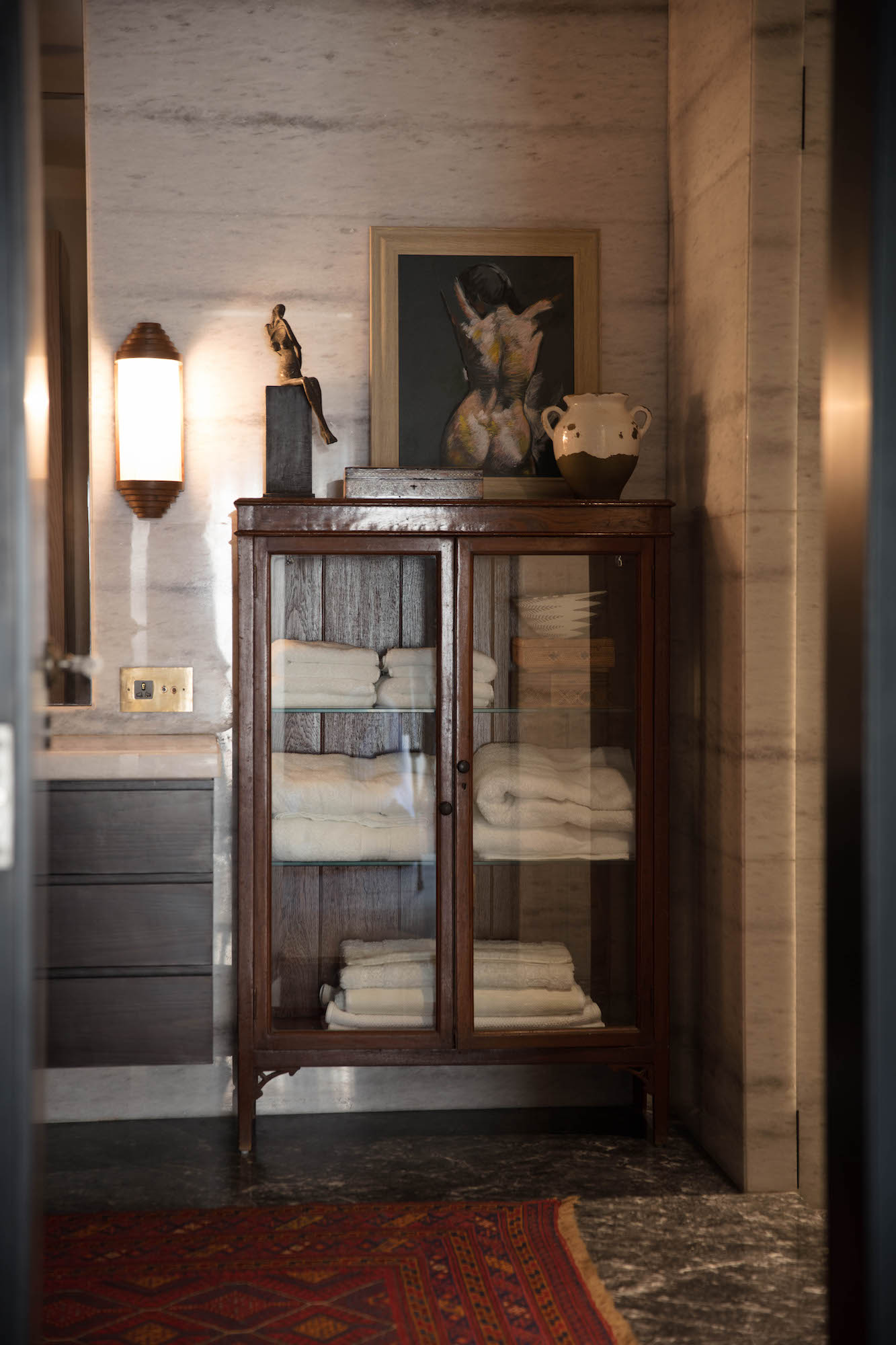 A traditional wood and glass bathroom cabinet with ceramics and art objects by Indian designer Ravi Vazirani